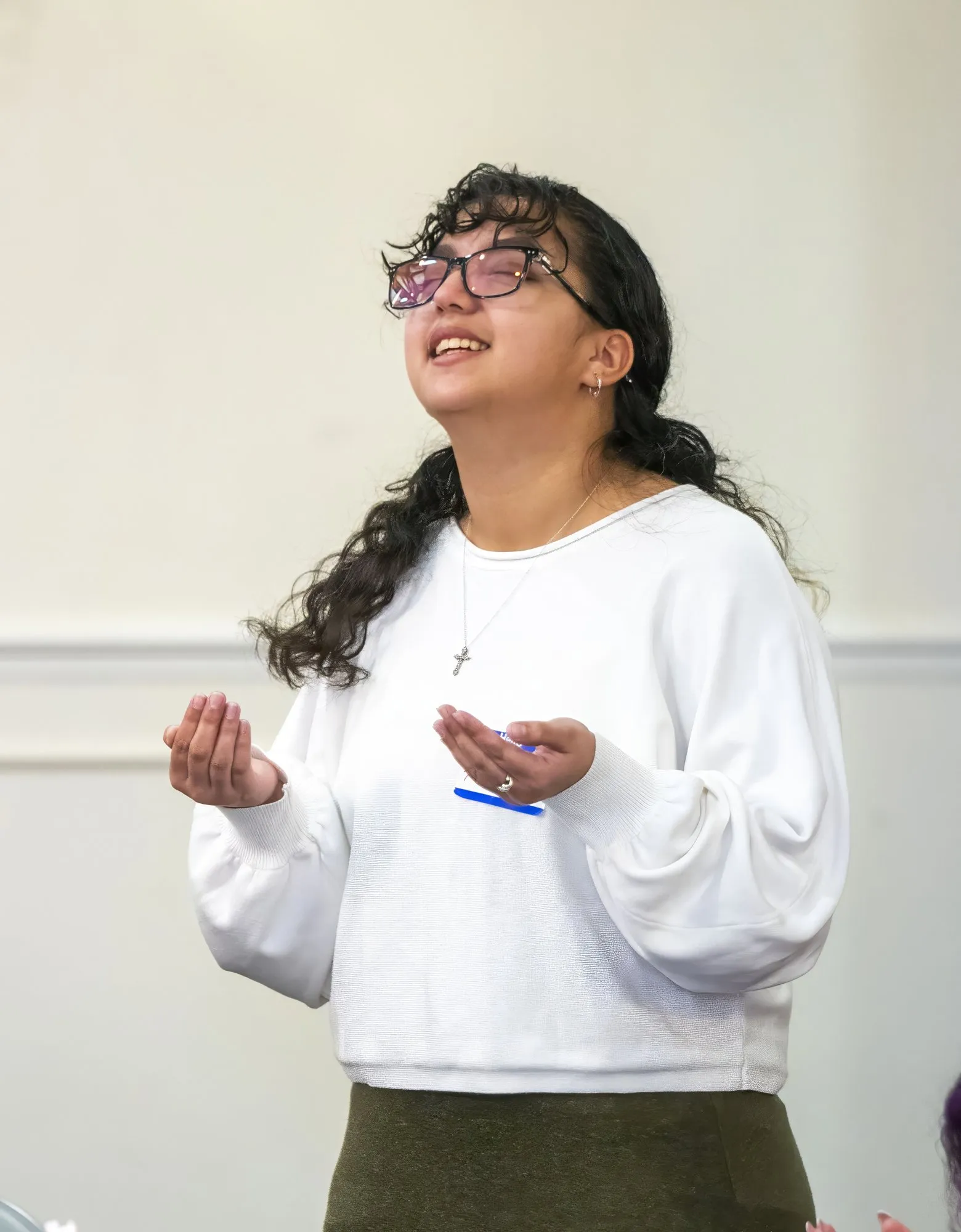 A young woman worshipping with her hands open at the 2026 conference