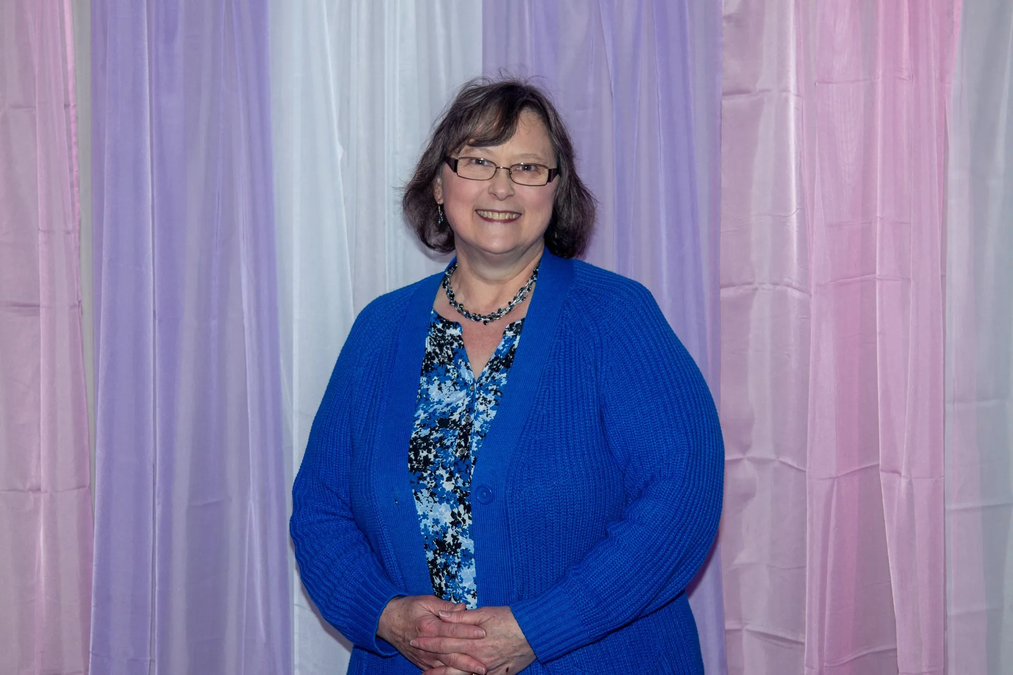 A woman in a blue cardigan at the entrance curtain