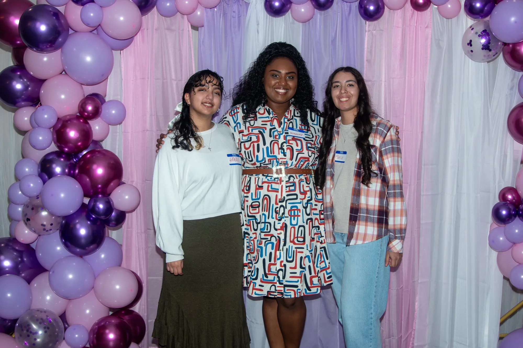 Three young women together at the entrance backdrop