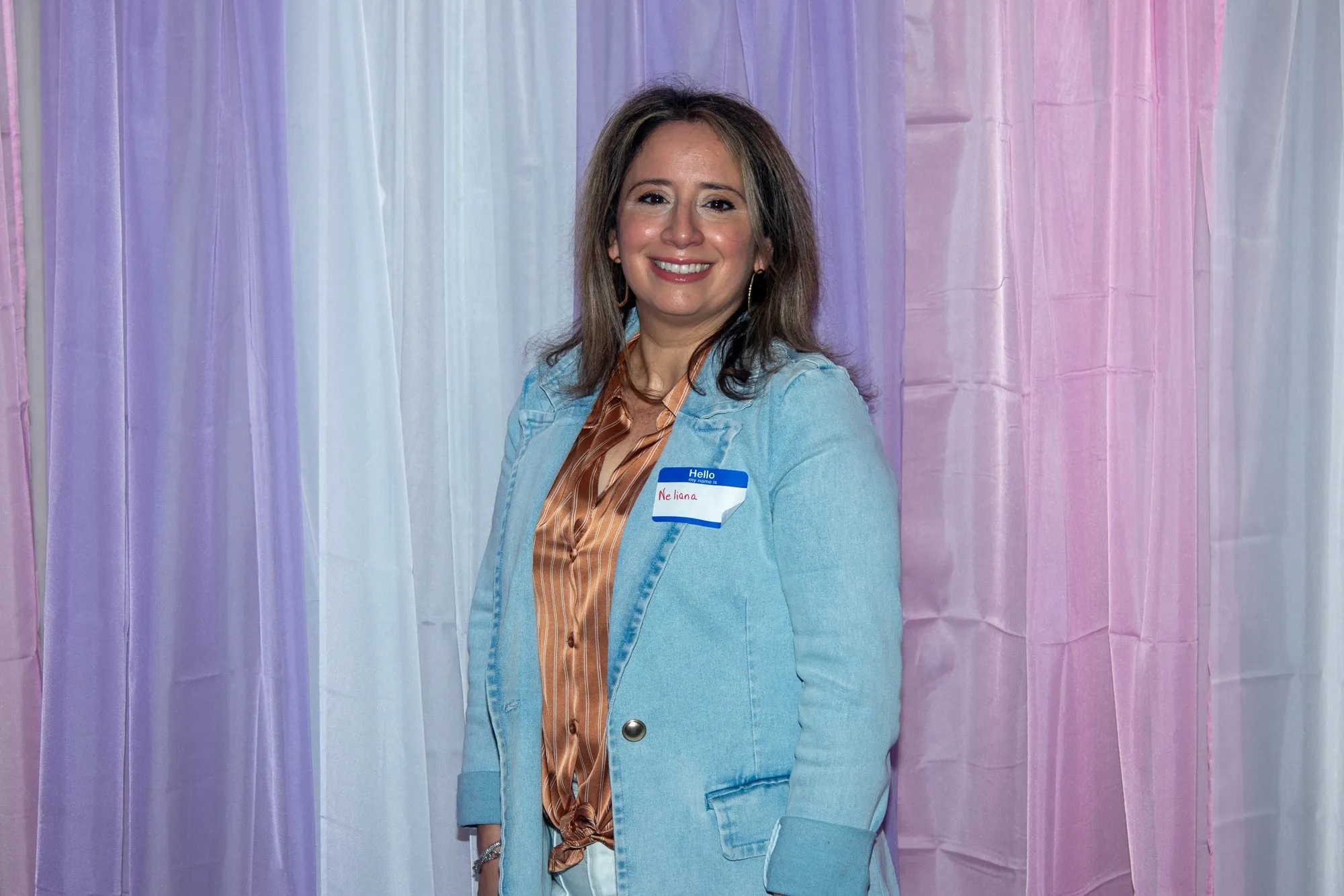 A woman in a blue cardigan at the entrance backdrop