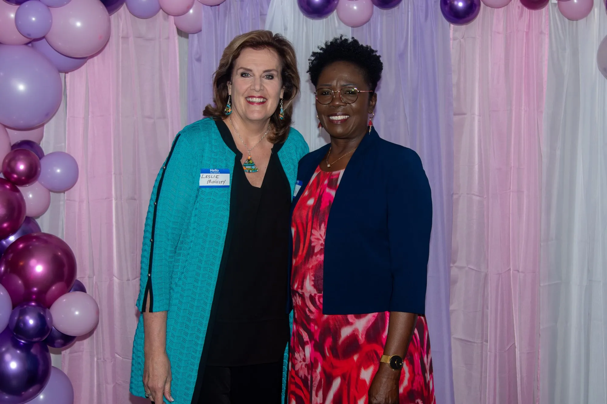 Two women side by side at the entrance backdrop