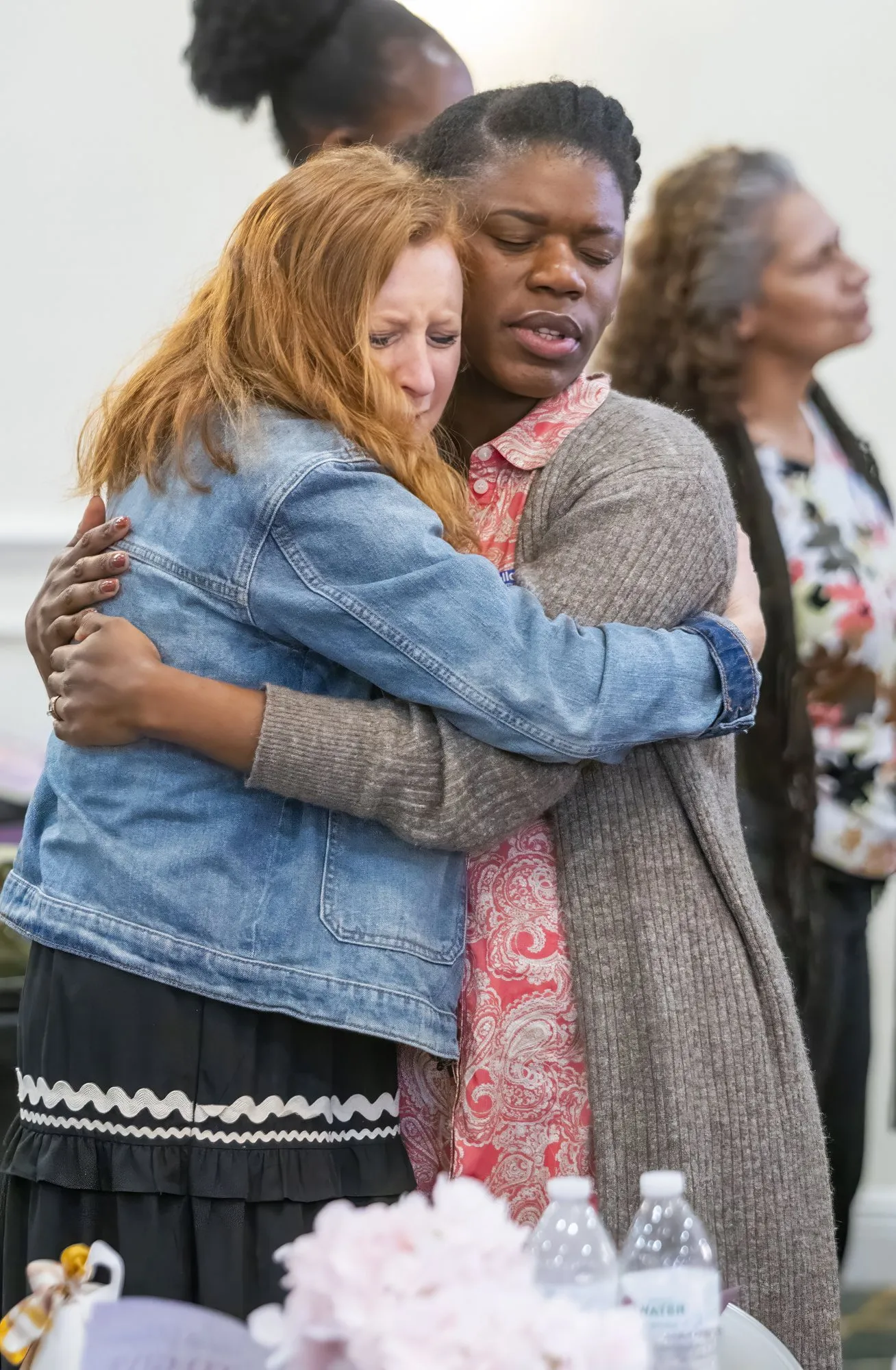Two women holding each other in prayer