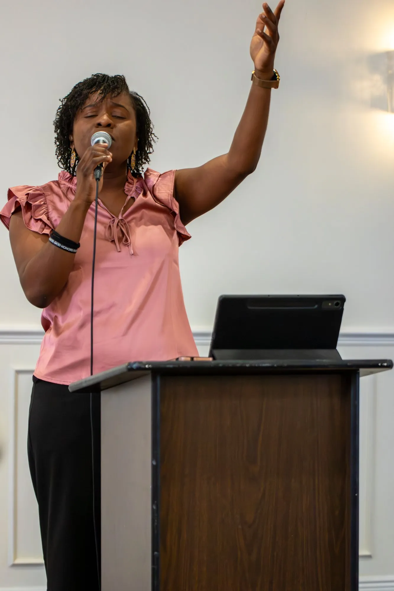 A worship leader singing with her arm raised
