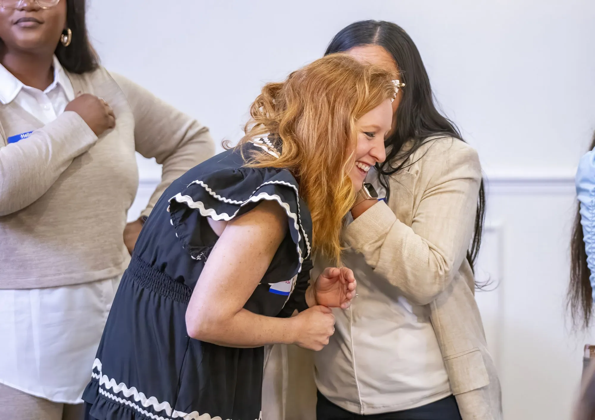 Women laughing together with their arms around each other