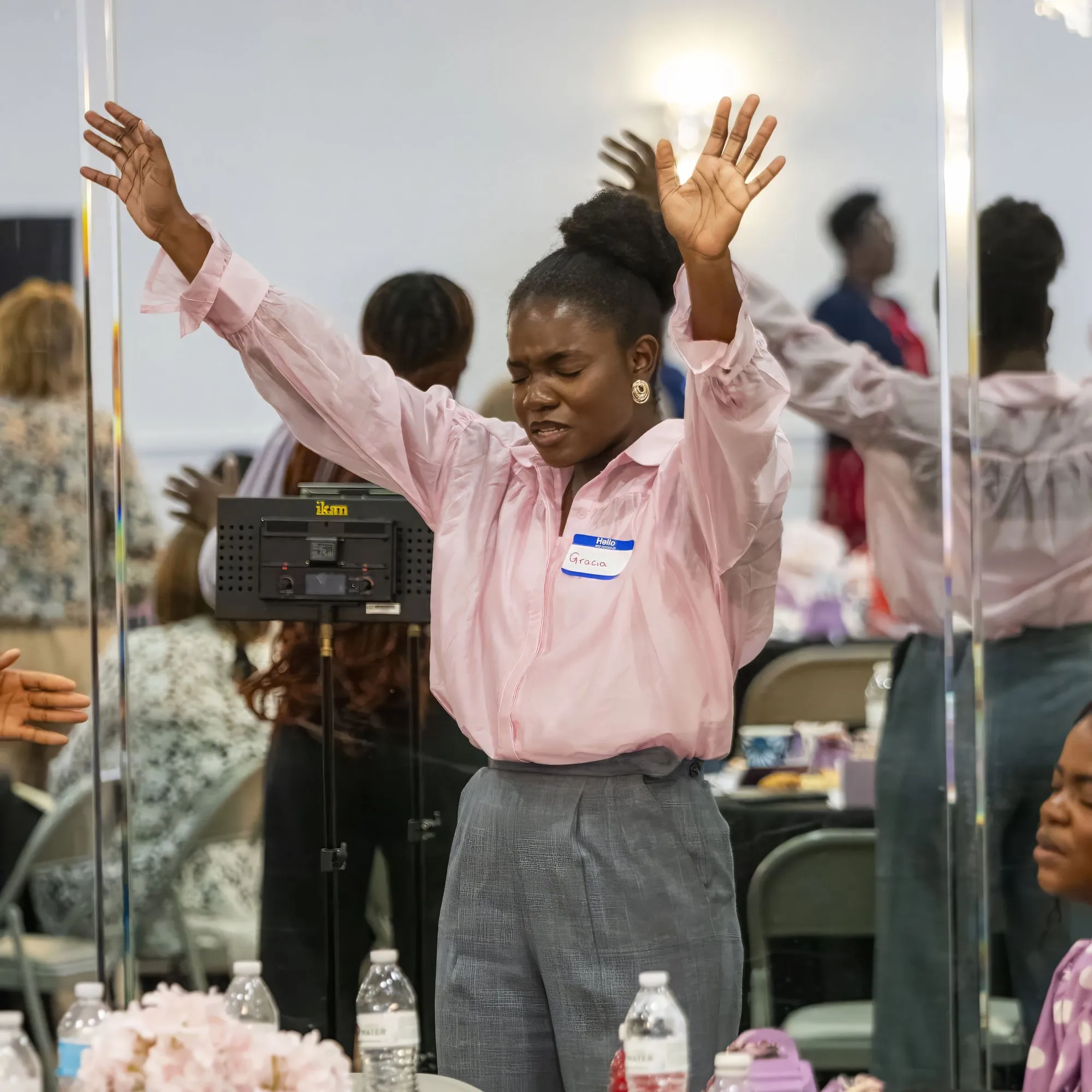 A young woman worshipping with both hands raised at the 2026 Ishah Purpose Conference