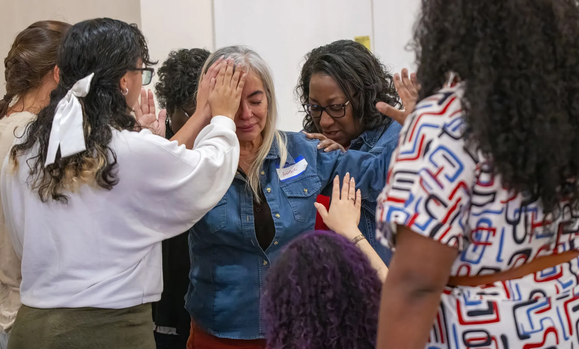 Women gathered around one woman, praying for her