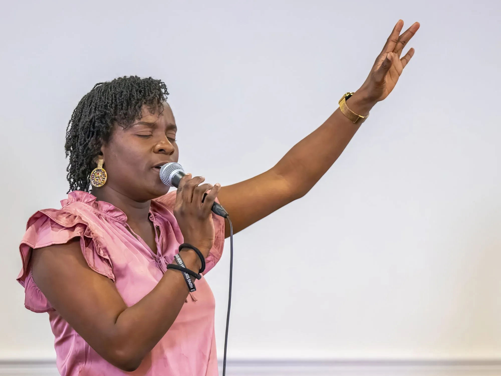 A worship leader singing with her hand raised